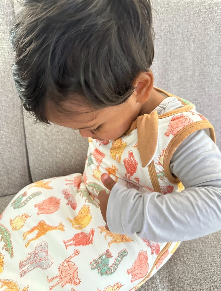 Child wearing a patterned outfit with cartoon characters on a neutral background