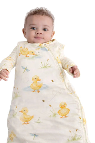 Baby wearing a sleeping bag with duck pattern on a white background