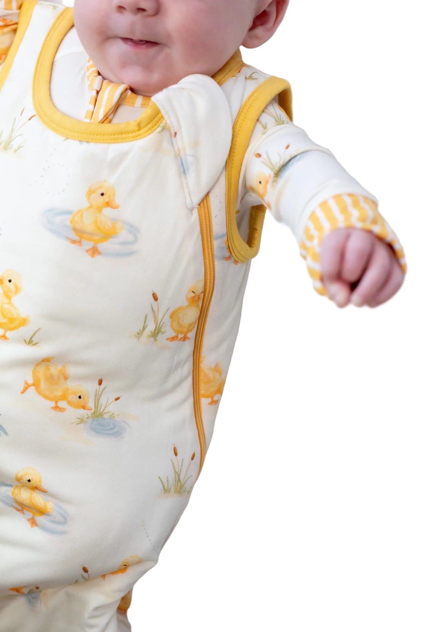 Baby wearing a yellow and white outfit with duck patterns on a white background