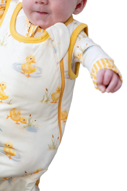 Baby wearing a yellow and white outfit with duck patterns on a white background