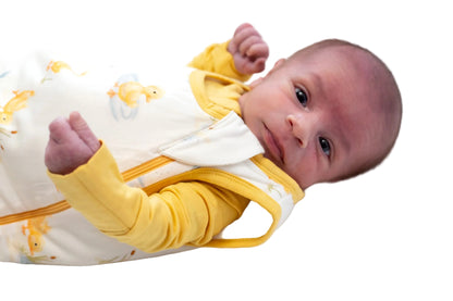 Newborn baby wearing a yellow and white bamboo sleep sack  on a white background