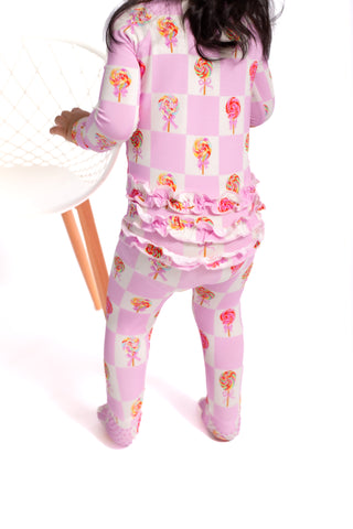 Child wearing a pink checkered outfit with floral patterns on a white background