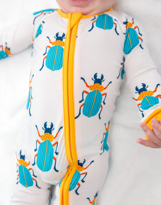 Baby wearing a onesie with beetle pattern and yellow zipper