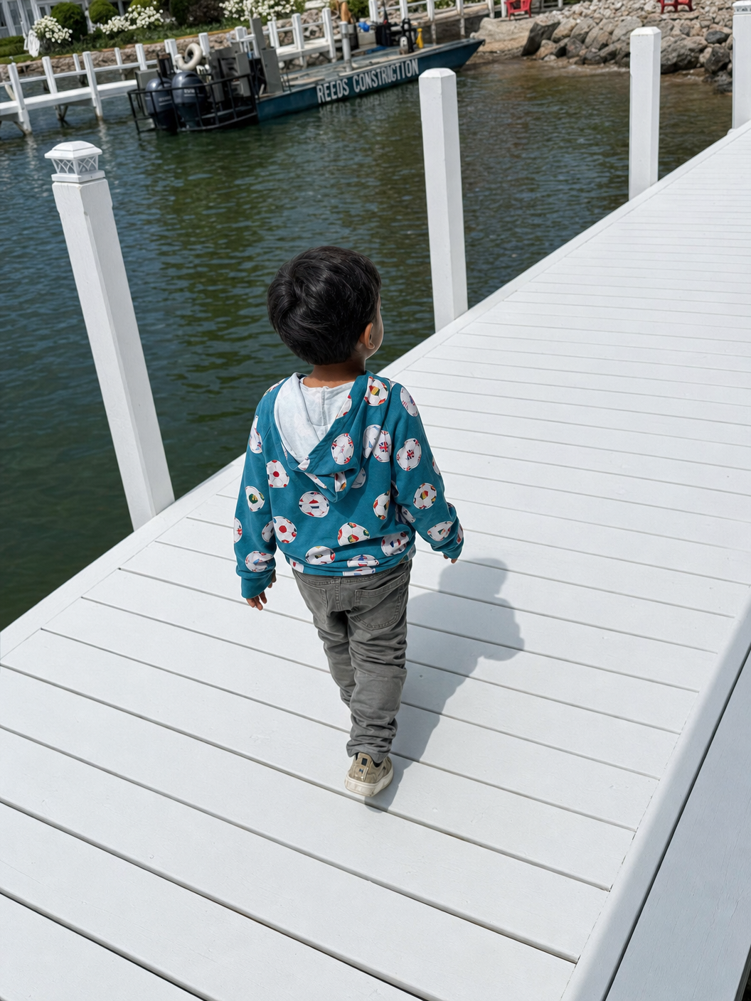 Child walking on a dock by a body of water