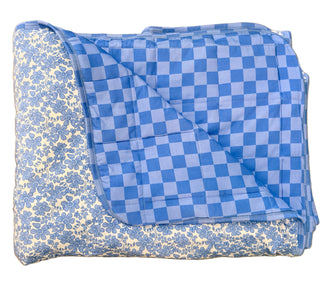Folded blue and white checkered blanket on a beige floor.
