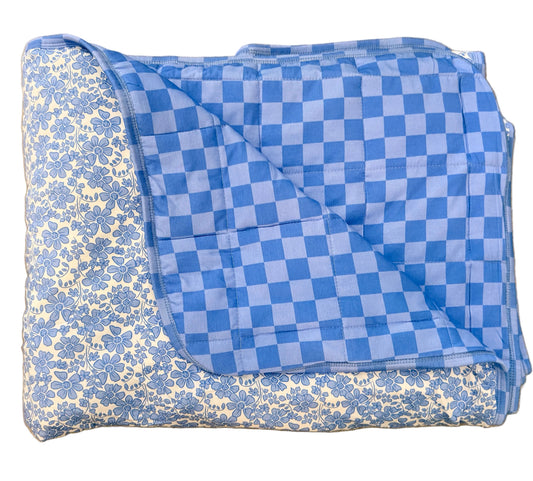 Folded blue and white checkered blanket on a beige floor.