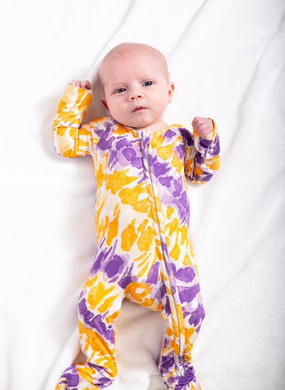 Baby wearing a colorful tie-dye onesie on a white background