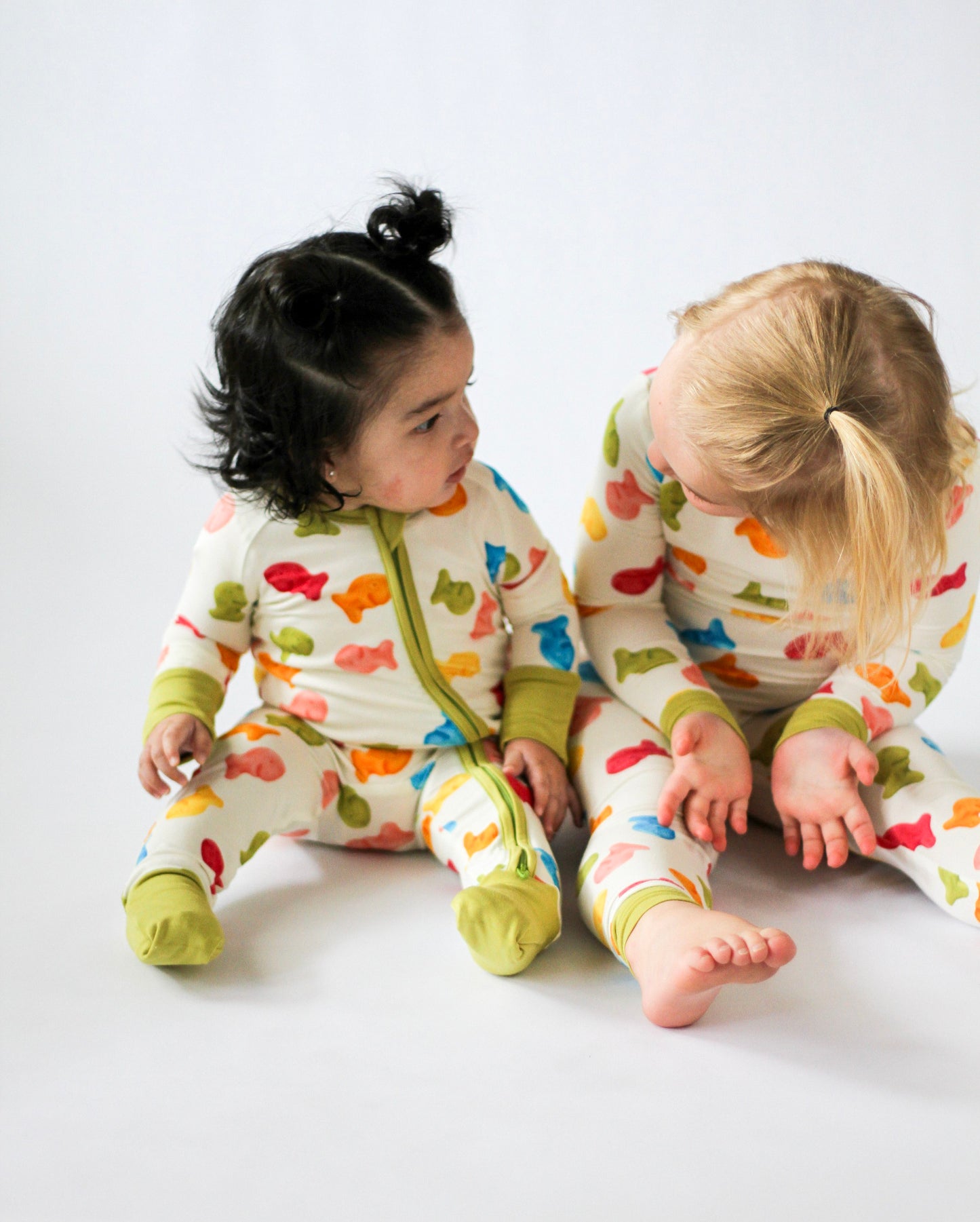 Two children wearing colorful pajamas with animal patterns on a white background