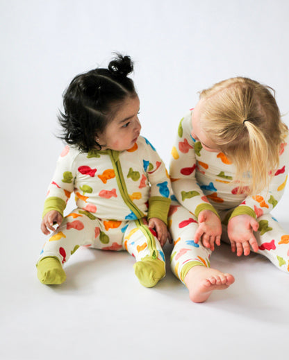 Two children wearing colorful pajamas with animal patterns on a white background
