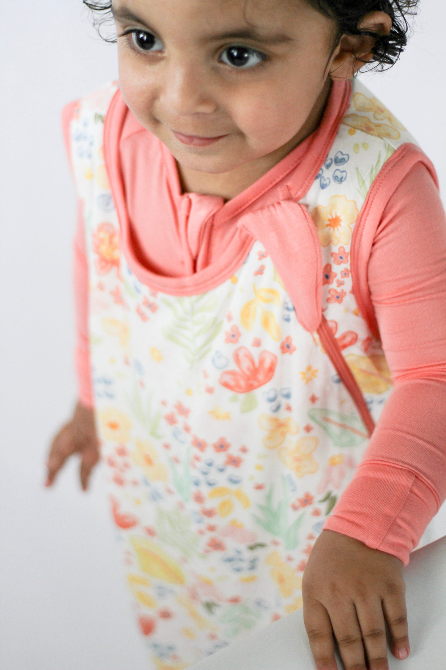 Child wearing a floral bib and pink shirt on a white background