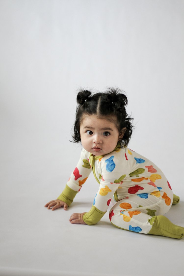 Child wearing a colorful onesie with fish pattern on a white background
