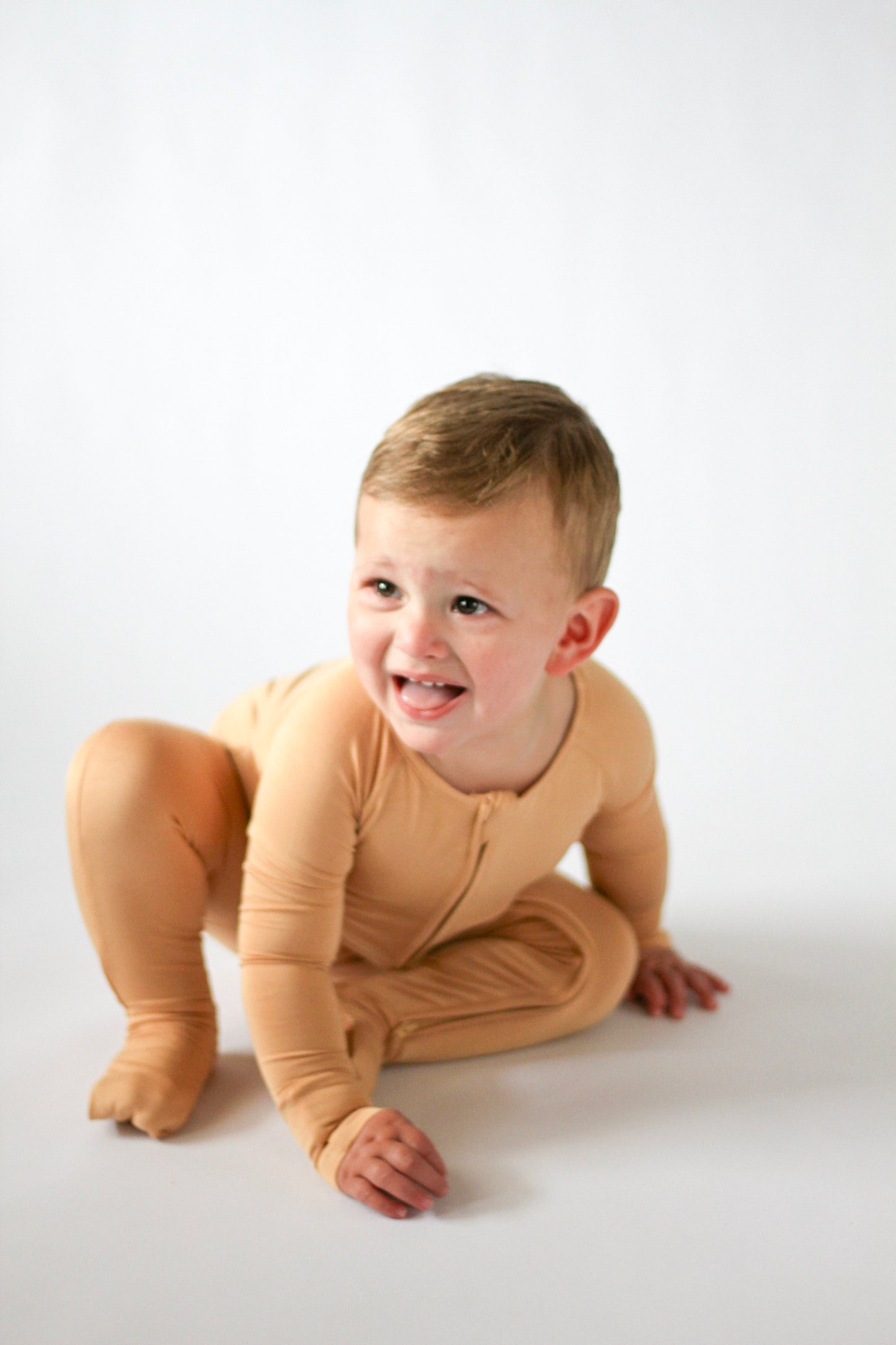 Child wearing a beige onesie on a white background