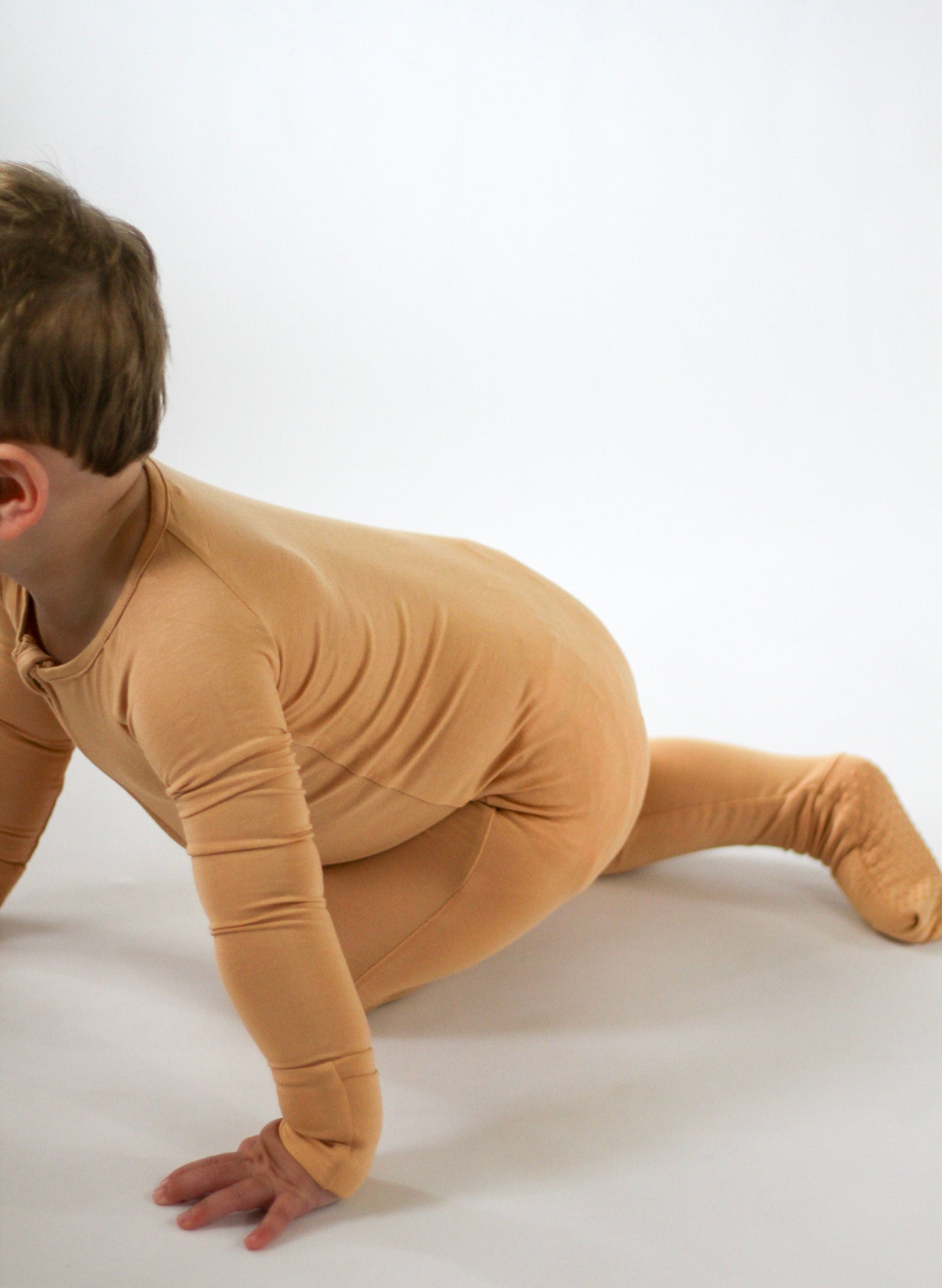 Child wearing a beige bodysuit on a white background