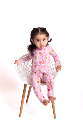 Child wearing a pink floral onesie sitting on a white chair with a white background