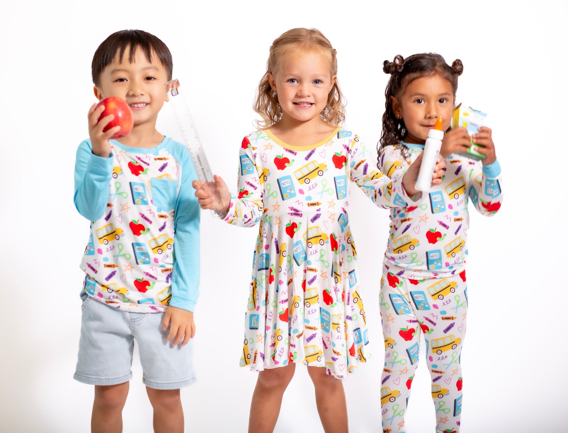 Three children wearing colorful pajamas with cartoon designs on a white background