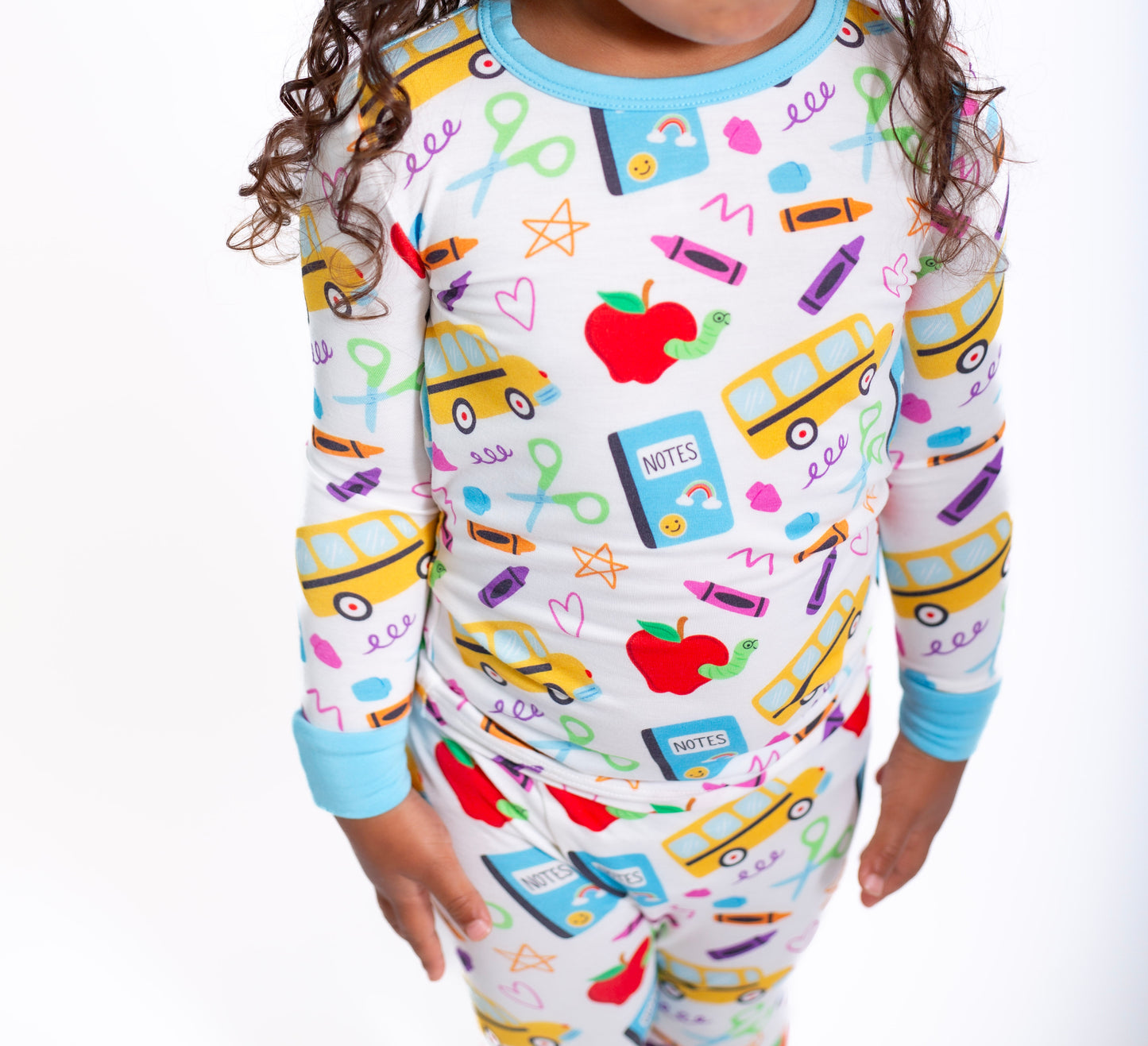 Child wearing a colorful pajama set with school-themed designs on a white background