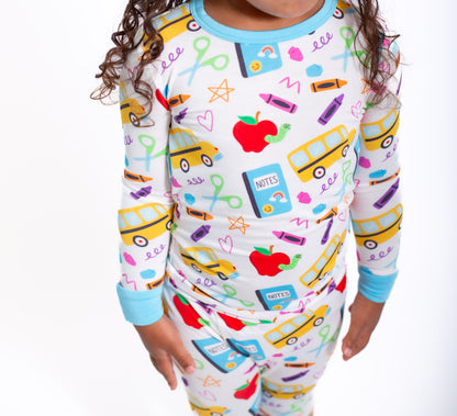Child wearing a colorful pajama set with school-themed designs on a white background