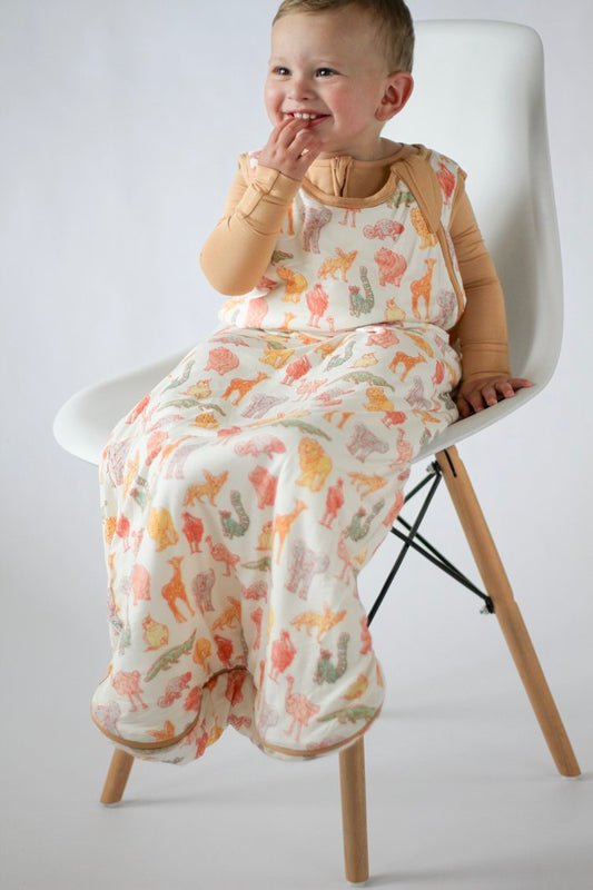 Child wearing a patterned baby wrap sitting on a chair against a white background