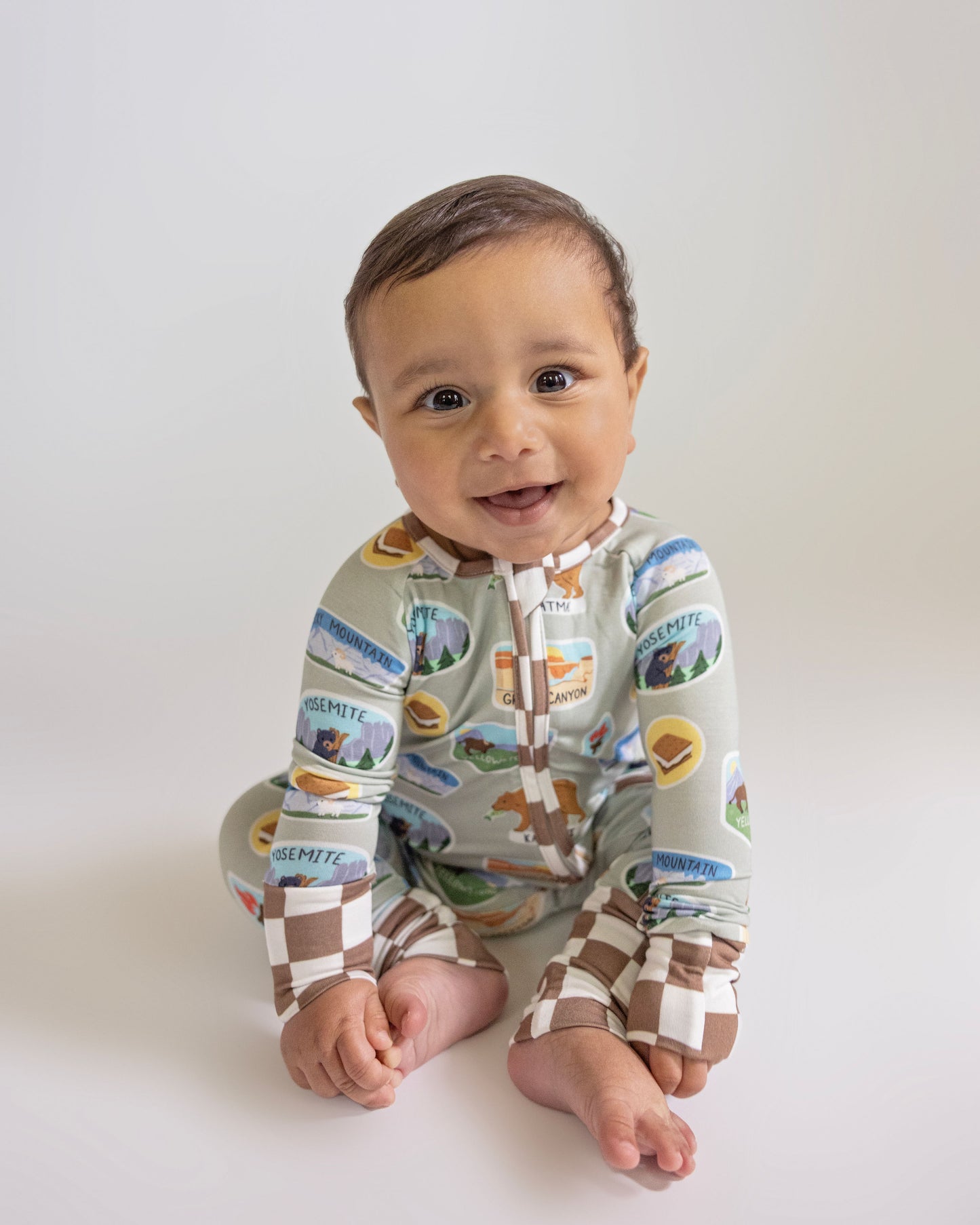 Baby wearing a colorful onesie with nature-themed design on a white background