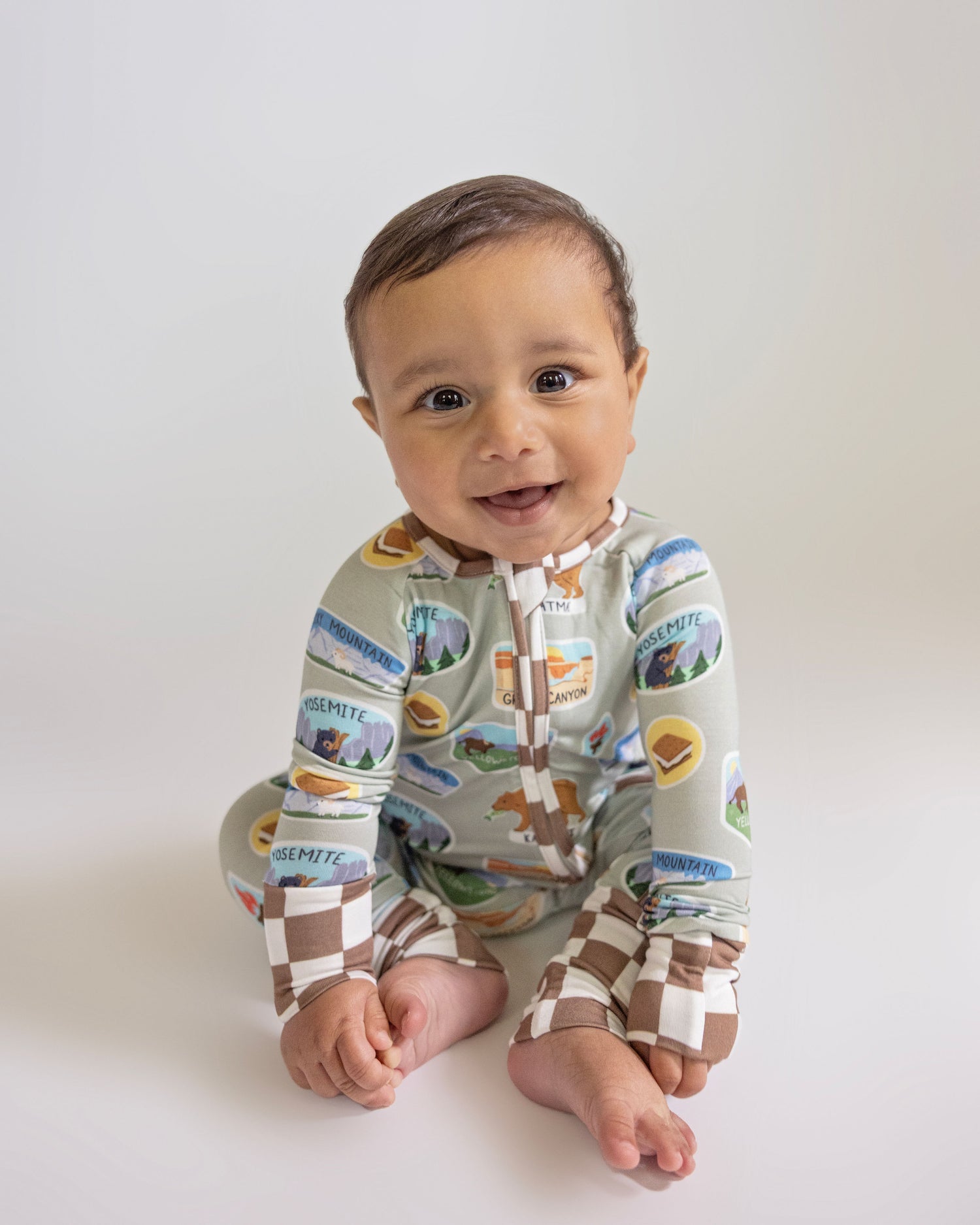 Baby wearing a colorful onesie with nature-themed design on a white background