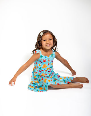 Young girl wearing a colorful dress with a pattern of fruits and vegetables on a white background