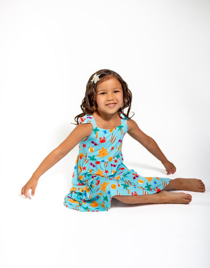 Young girl wearing a colorful dress with a pattern of fruits and vegetables on a white background