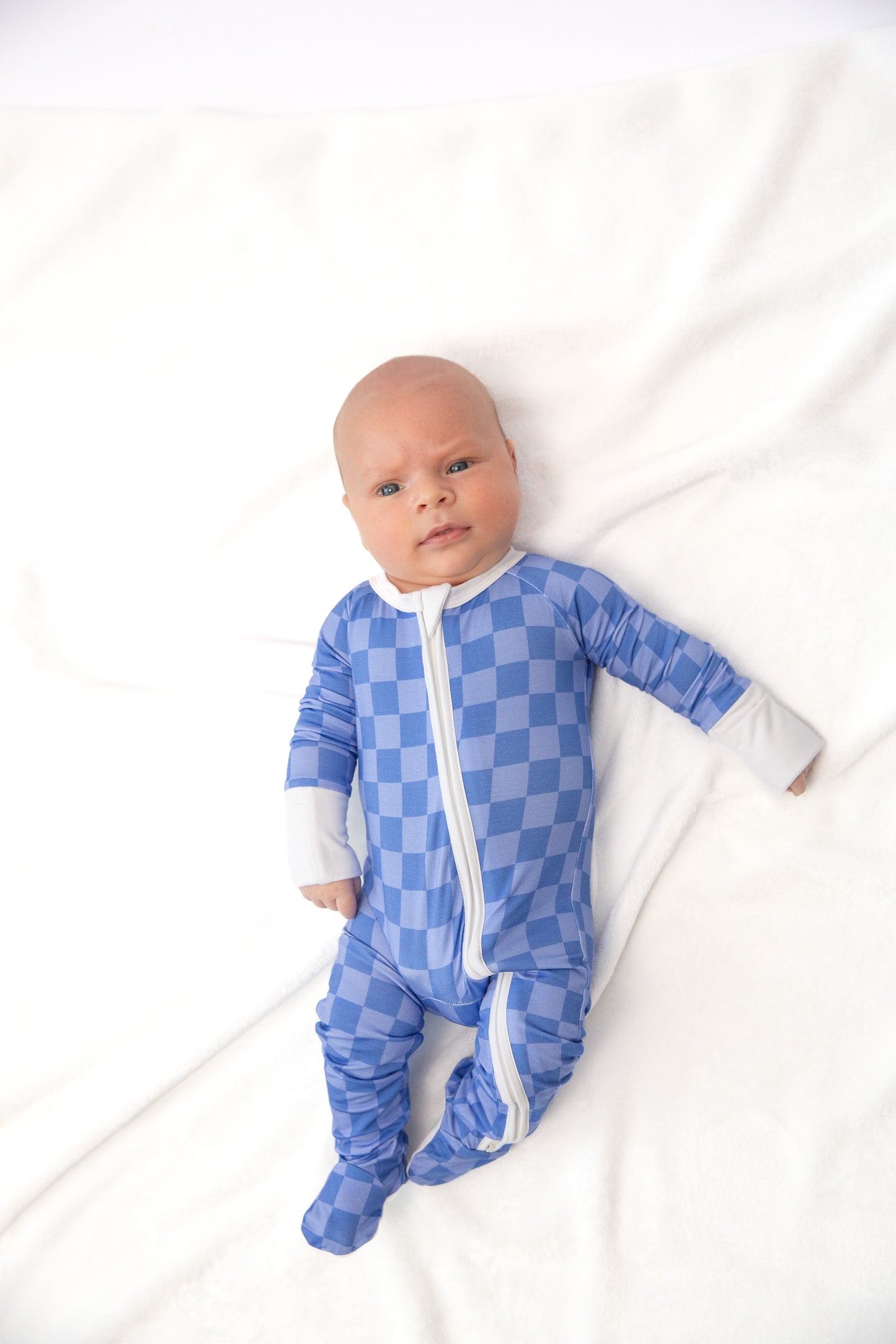 Baby wearing a blue checkered onesie on a white background