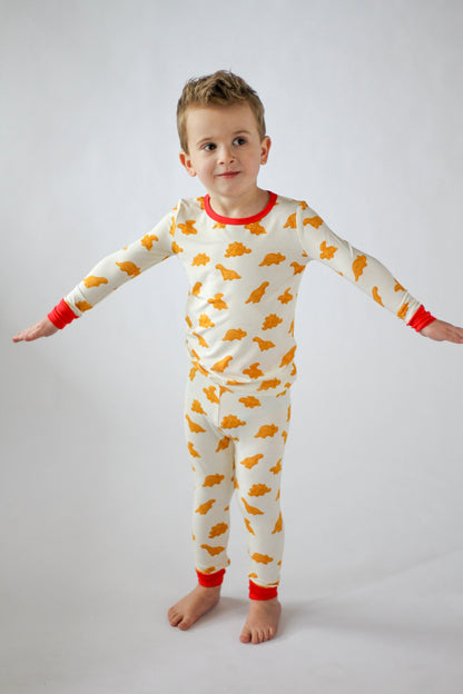 Child wearing a white onesie with orange patterns on a plain background