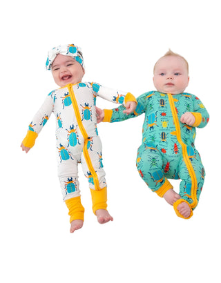 Two babies wearing colorful onesies with insect patterns on a white background