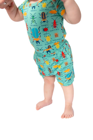 Child wearing a colorful romper with insect design on a white background