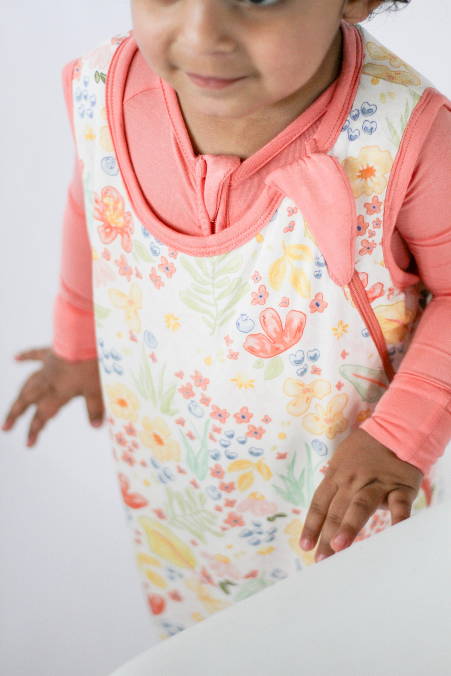 Child wearing a floral apron with a pink shirt on a white background
