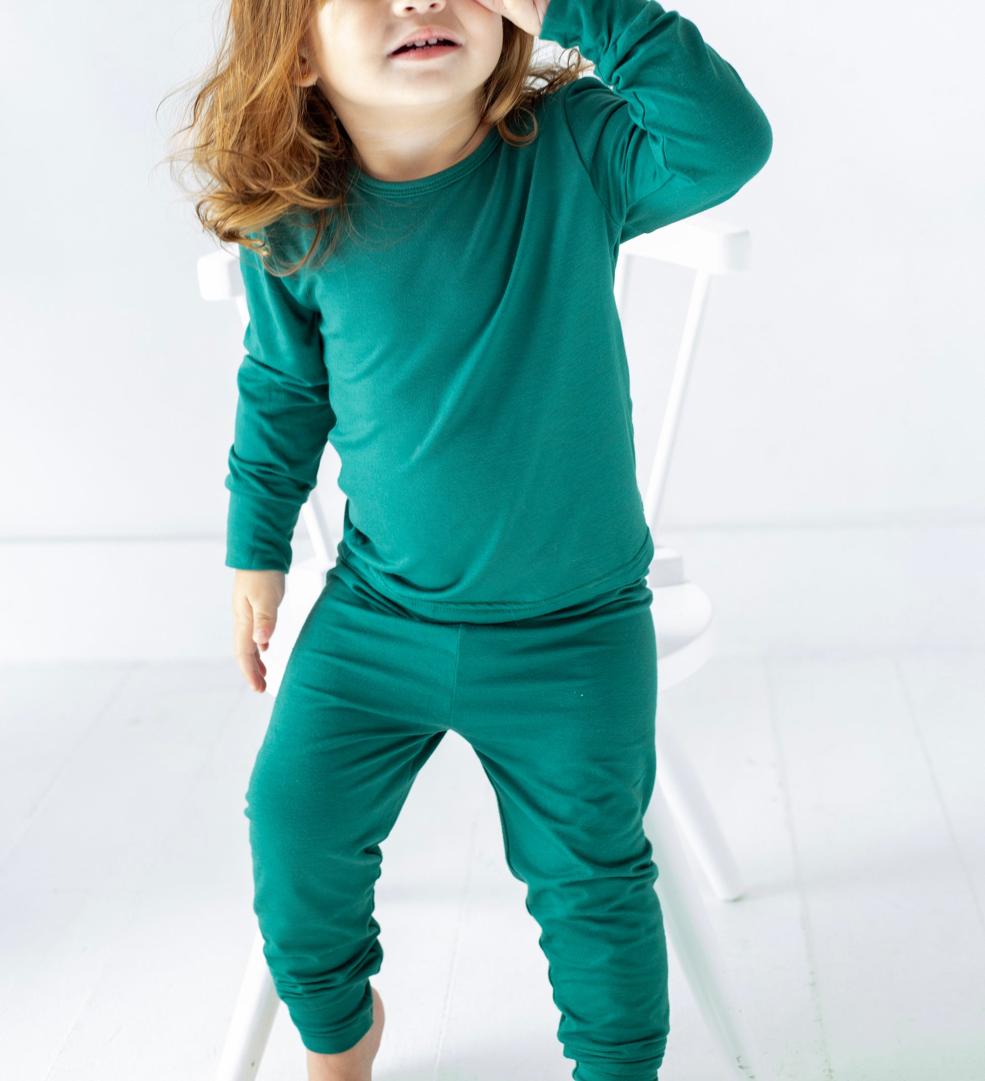 Child wearing a green outfit on a white background