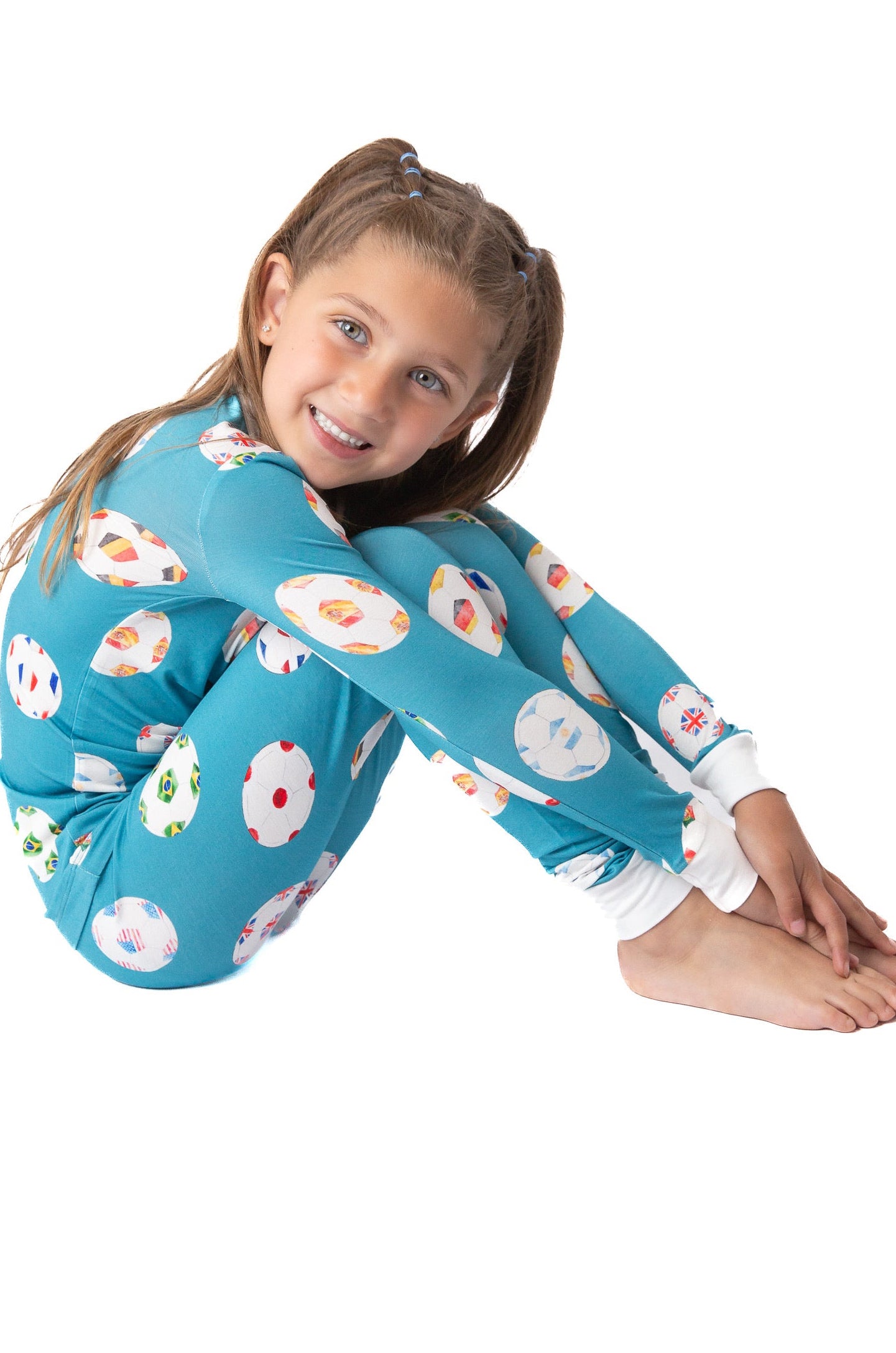Child wearing a blue floral onesie sitting on a white background