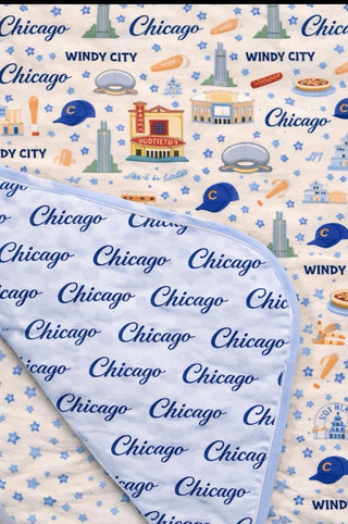 A luxury reversible bamboo blanket featuring playful Chicago-inspired artwork on one side and elegant light blue Chicago script on the other, designed for cozy moments, home décor, and meaningful family memories.