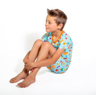 Child wearing a colorful swimsuit with an underwater pattern on a white background
