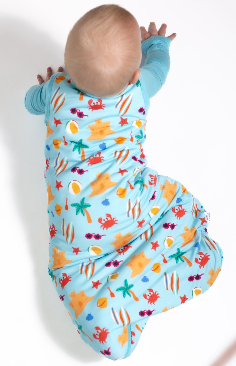 Baby in a colorful sea-themed swaddle on a white background