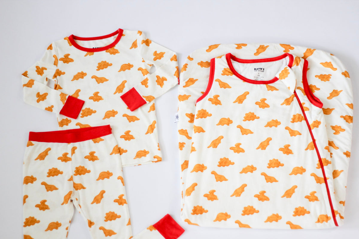 Two baby onesies with orange patterns and red accents on a white background
