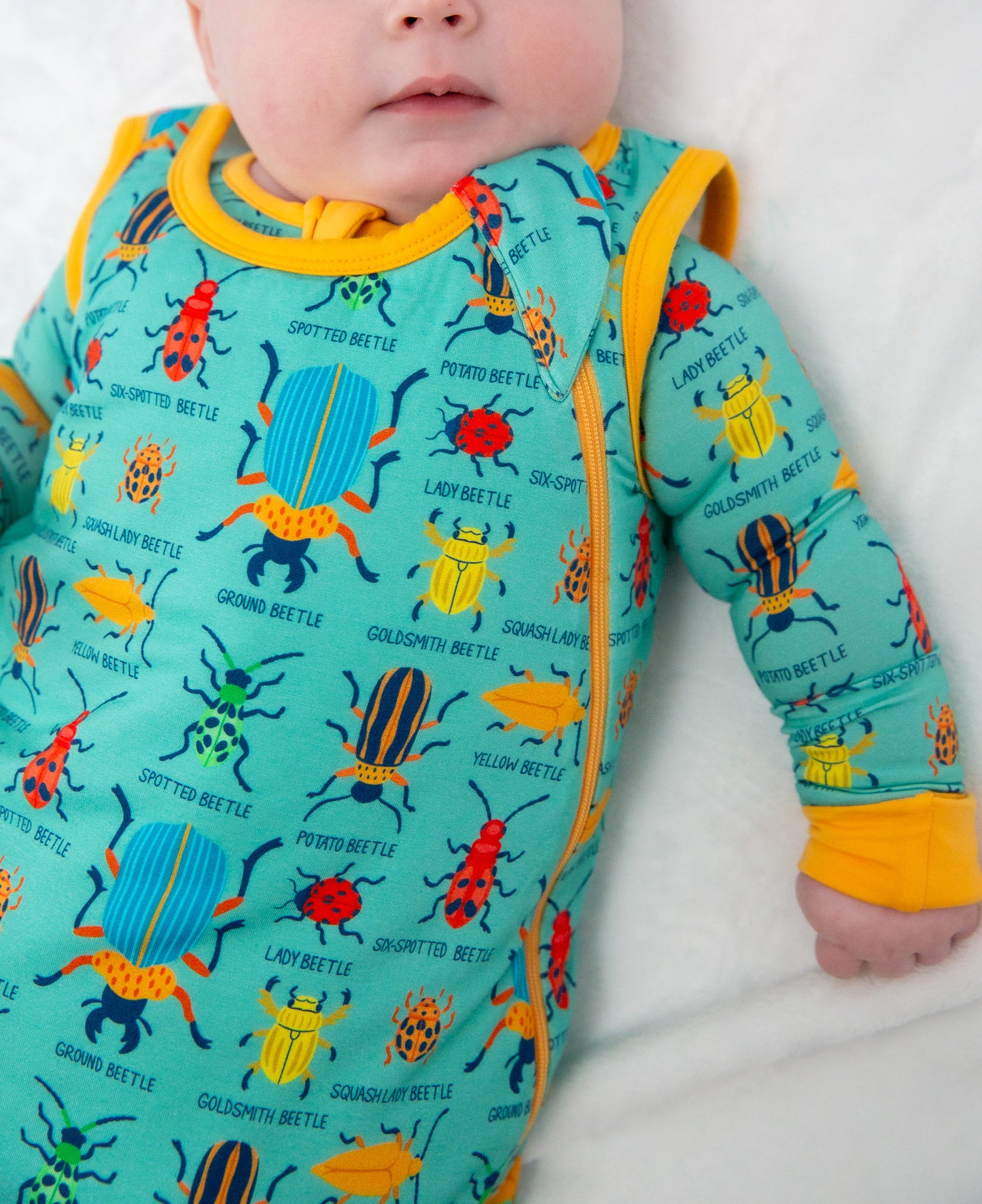 Baby wearing a colorful beetle-patterned onesie on a white background