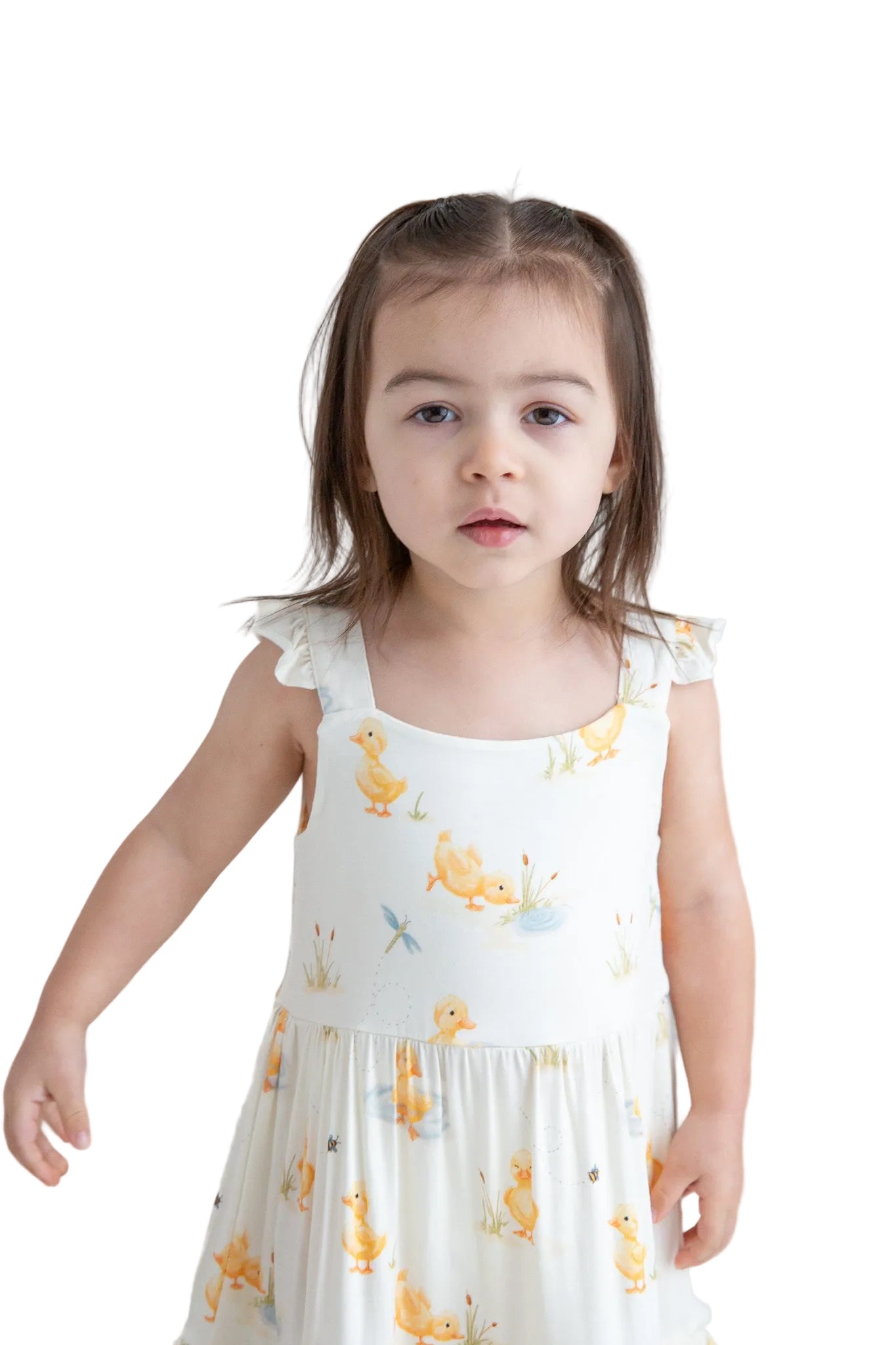 Young girl wearing a white dress with yellow duck patterns against a plain background