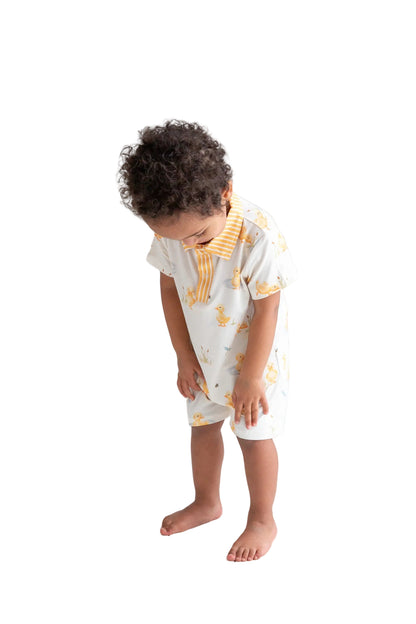Child wearing a white outfit with yellow patterns on a white floor and background
