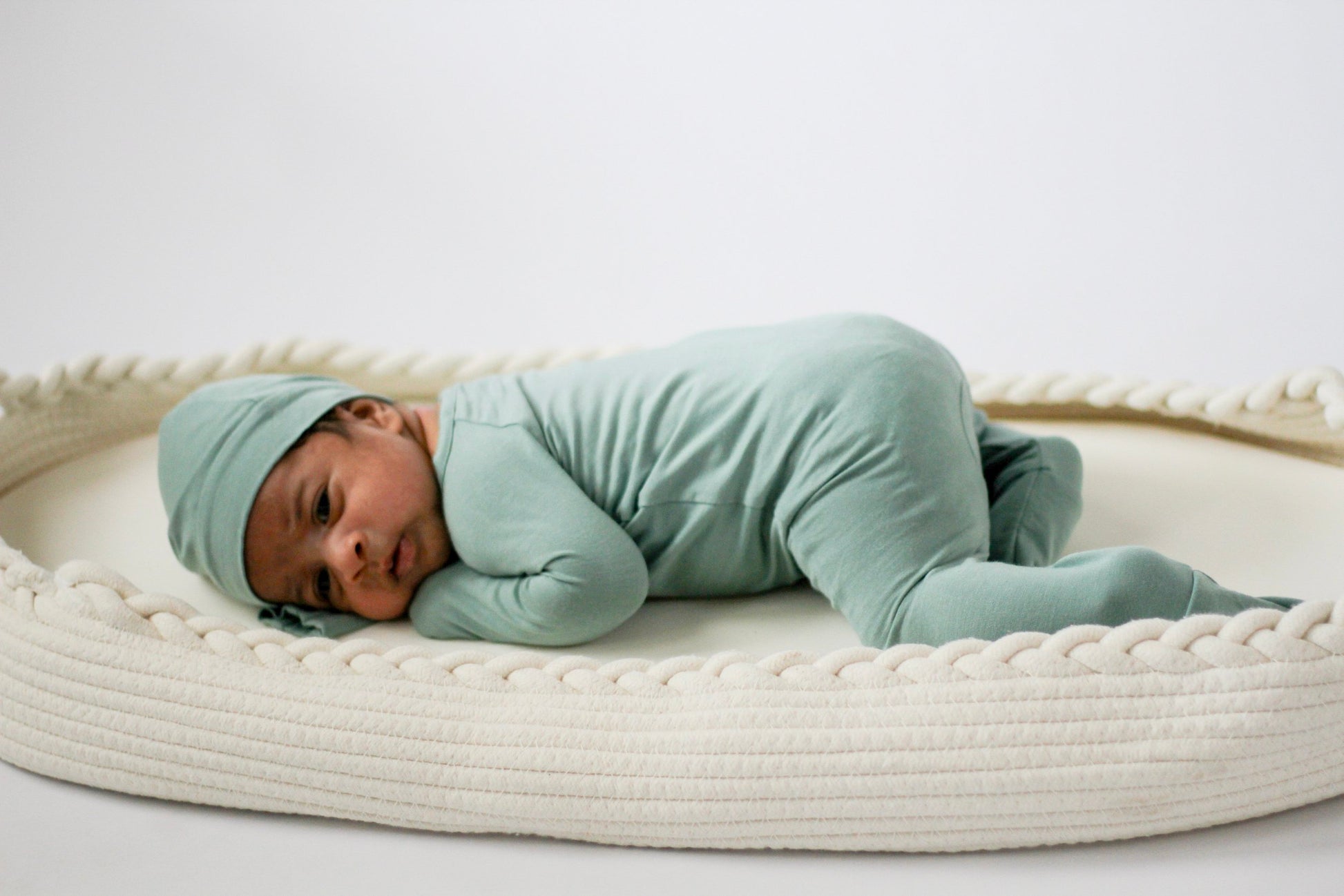 Baby lying on a white woven mat with a plain background