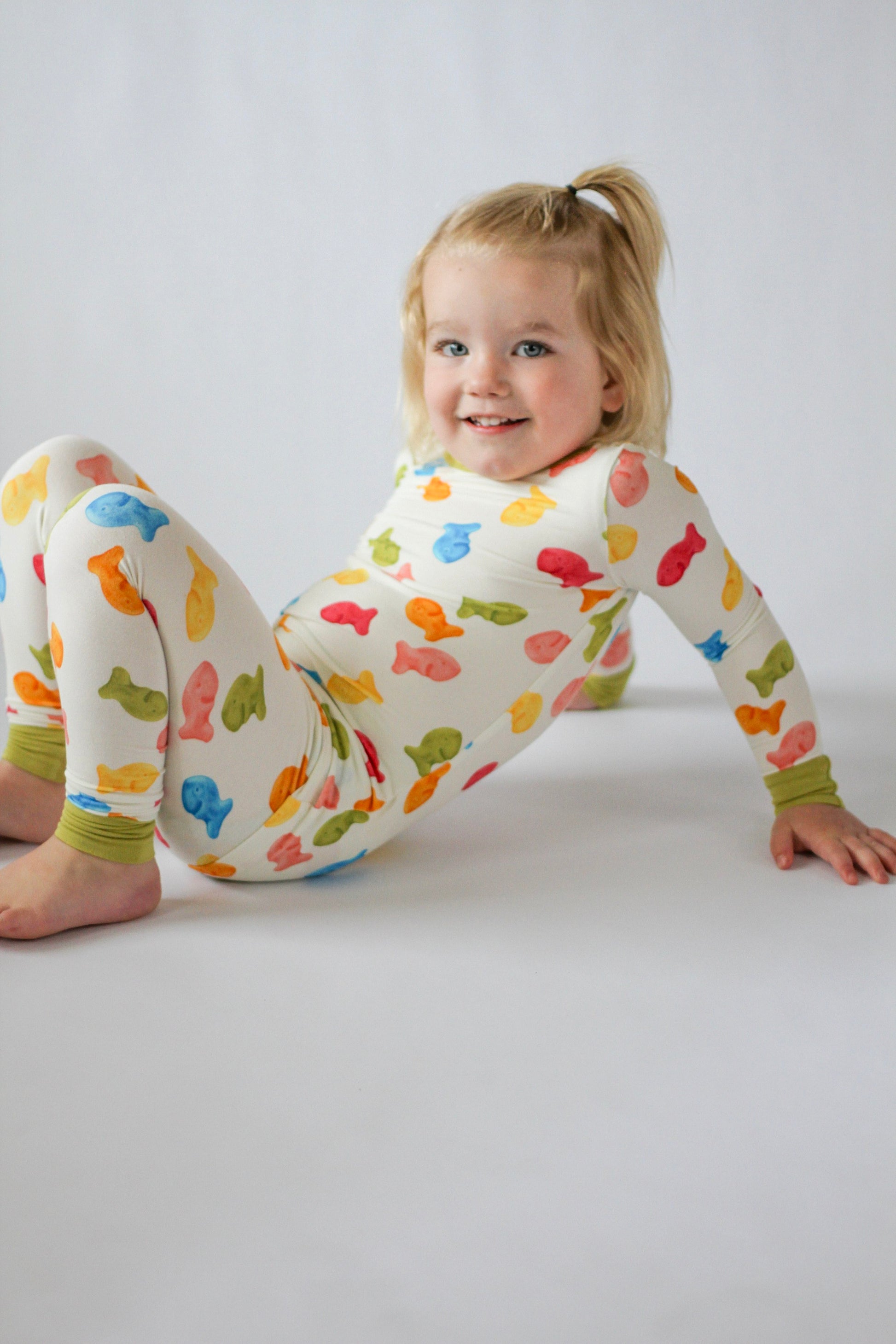 Child wearing a colorful outfit with animal patterns on a plain background