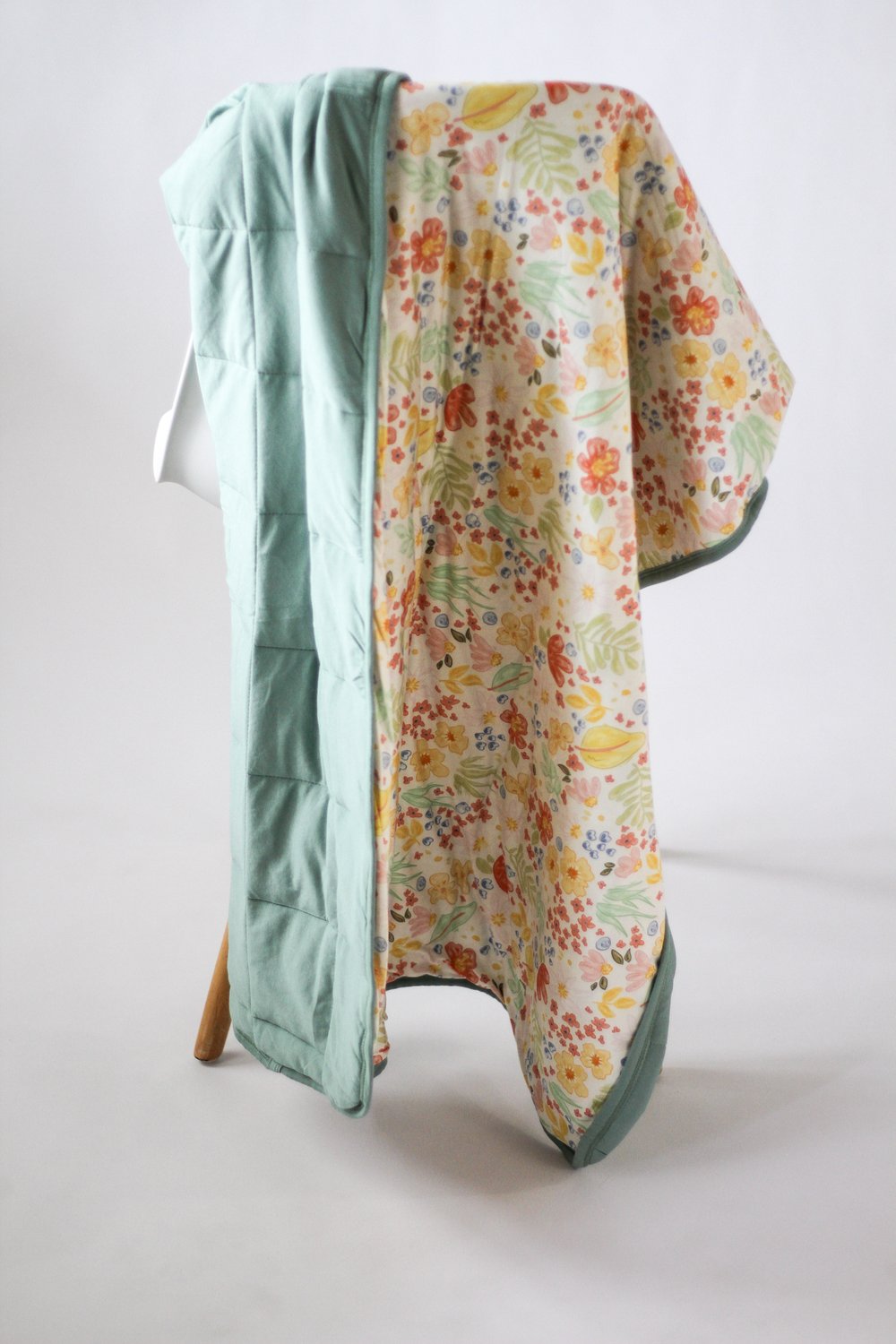 Floral-patterned blanket draped over a chair on a white background