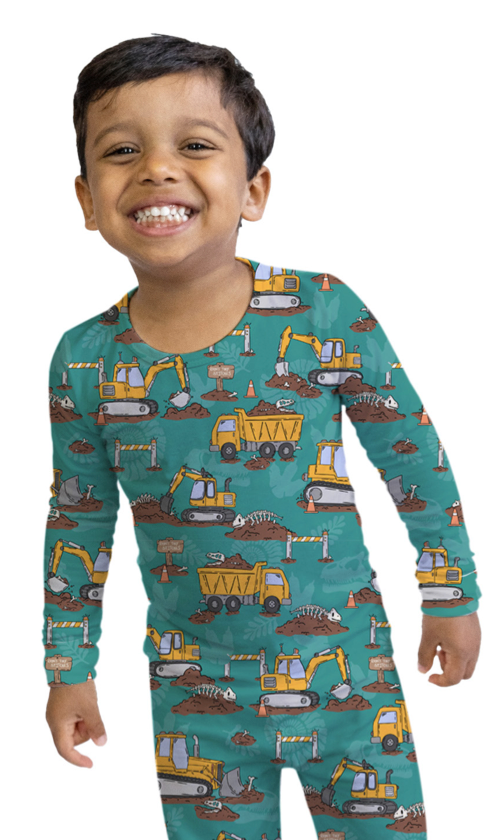Child wearing a teal onesie with construction vehicle pattern on a white background