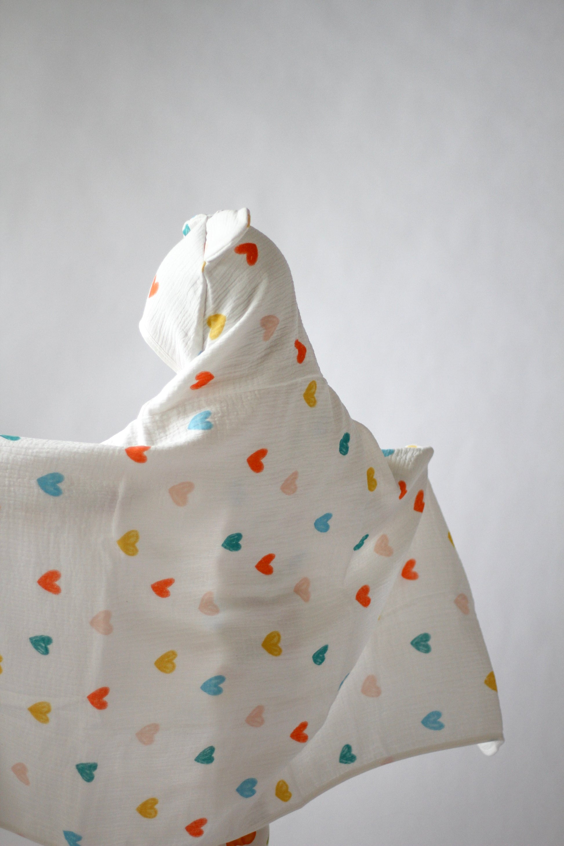 White hooded blanket with colorful heart patterns on a plain background
