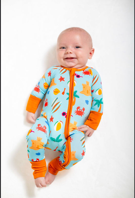 Baby wearing a colorful onesie with orange and blue design on a white background