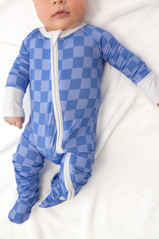 Baby wearing a blue checkered onesie on a white background