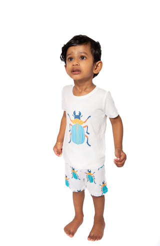 Child wearing a white outfit with beetle designs on a white background