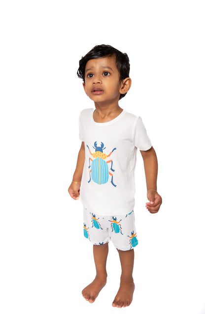 Child wearing a white outfit with beetle designs on a white background