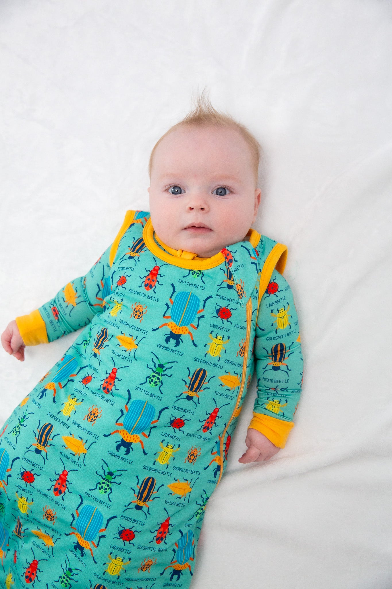 Baby wearing a colorful pajama with insect patterns on a white background